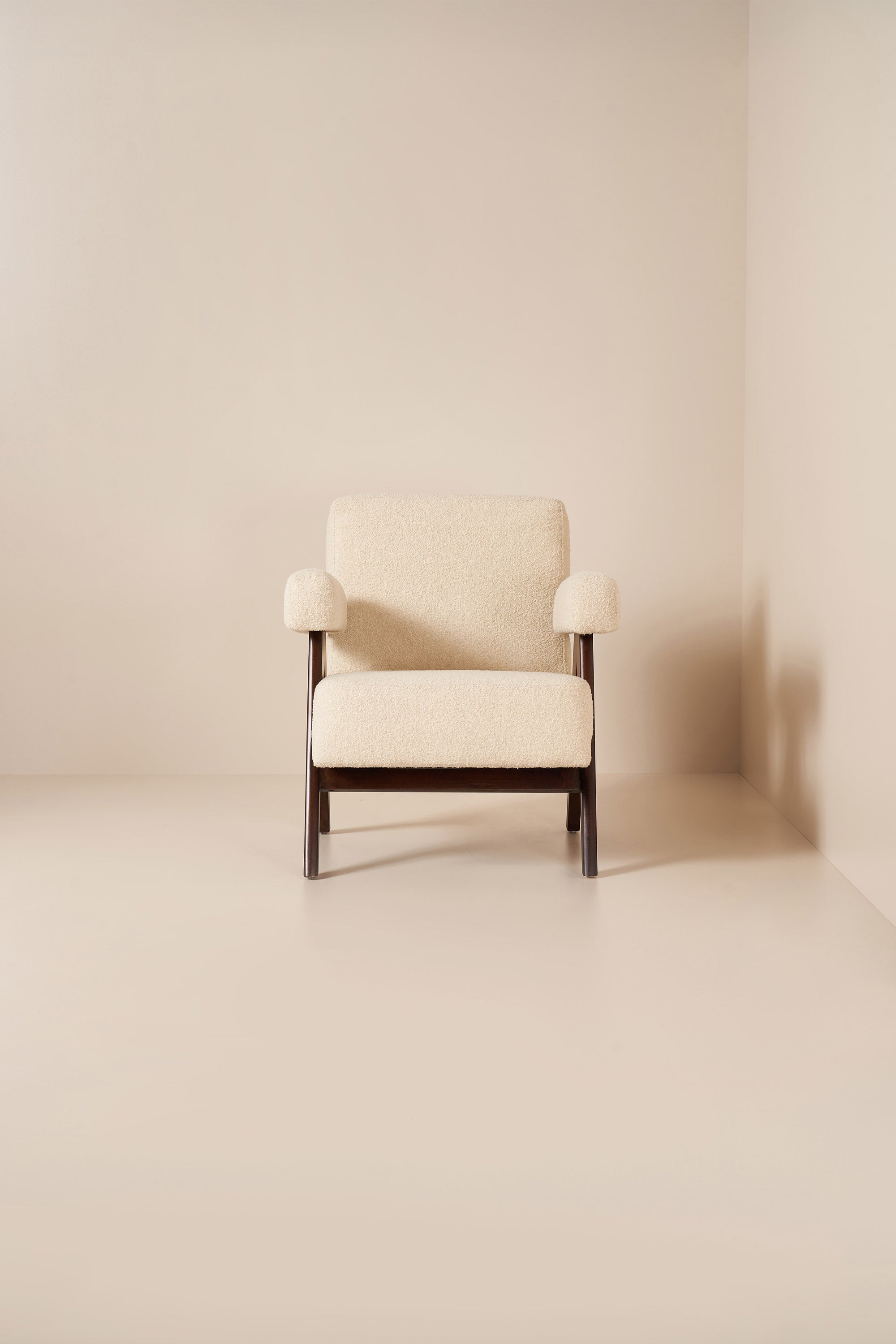 Beige armchair in a minimalistic room with beige walls and floor.