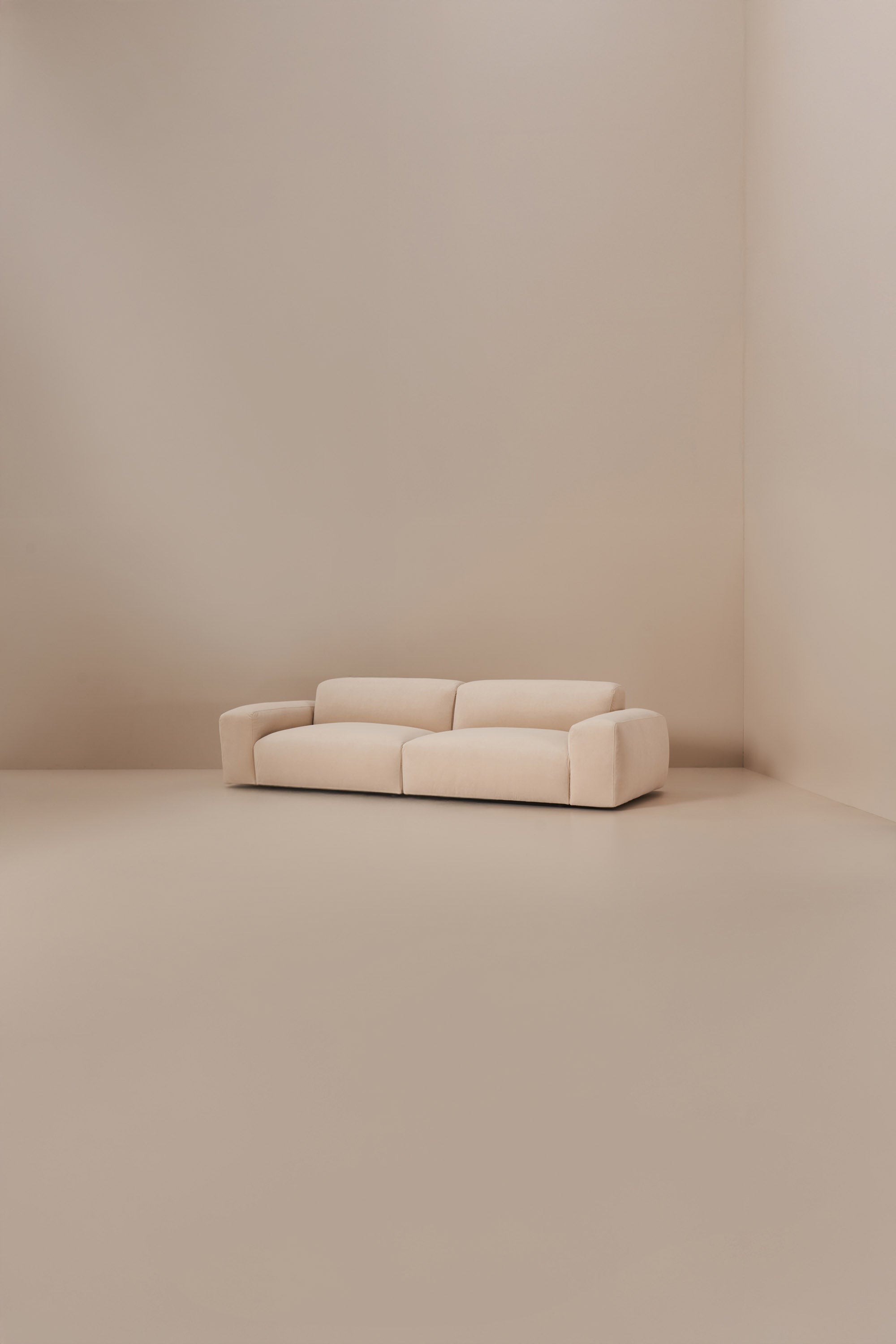 Beige modular sofa in a minimalistic room with beige walls and floor