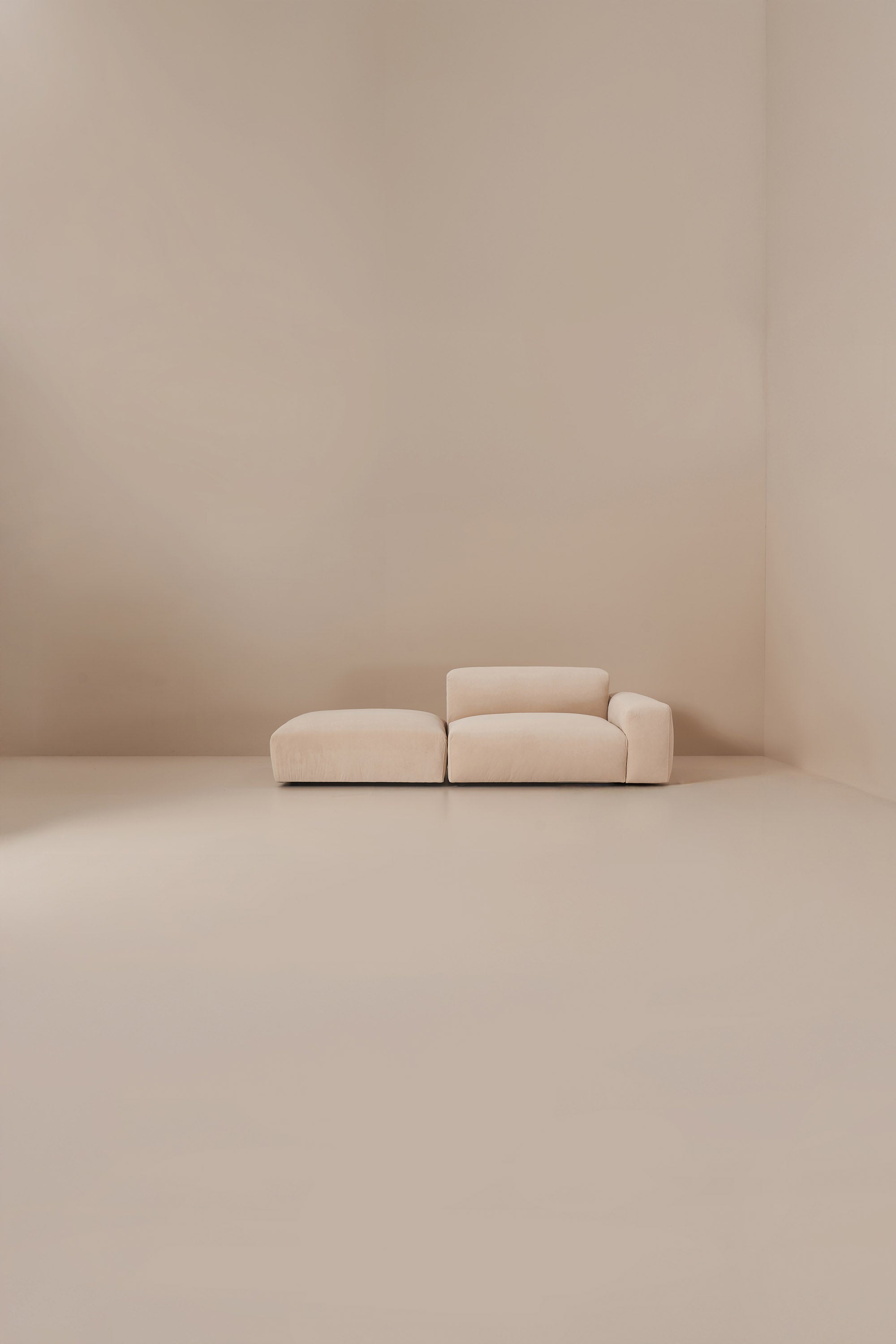 Beige sofa in a minimalistic room with beige walls and floor.