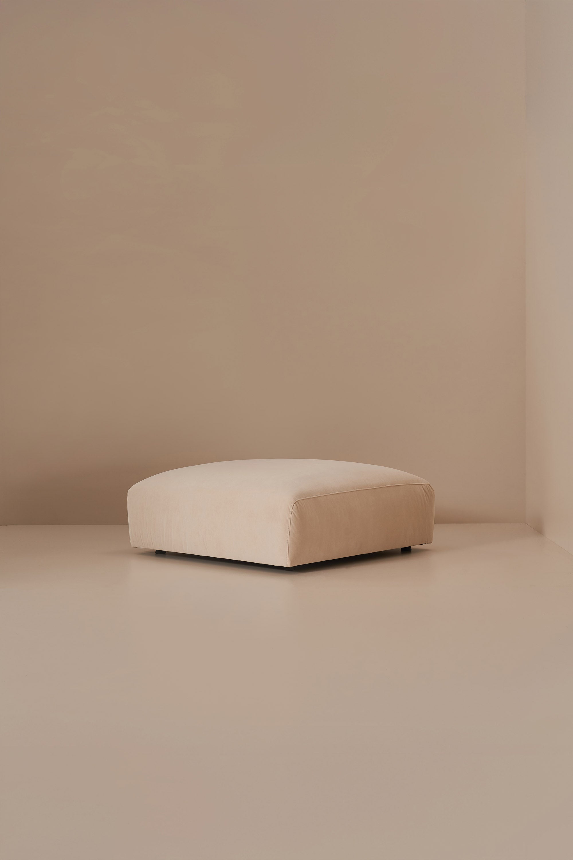 Beige pouffe in a minimalistic room with beige walls and floor.