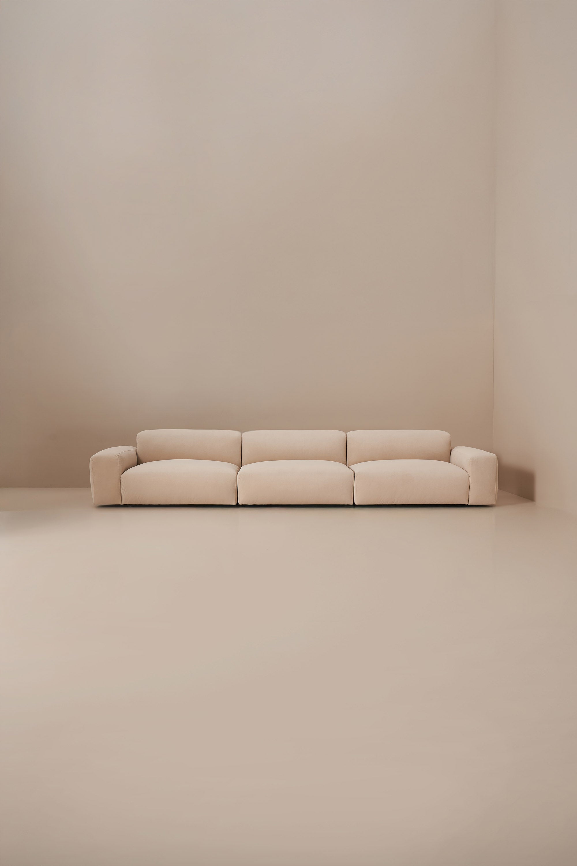 Beige sofa in a minimalistic room with beige walls and floor.