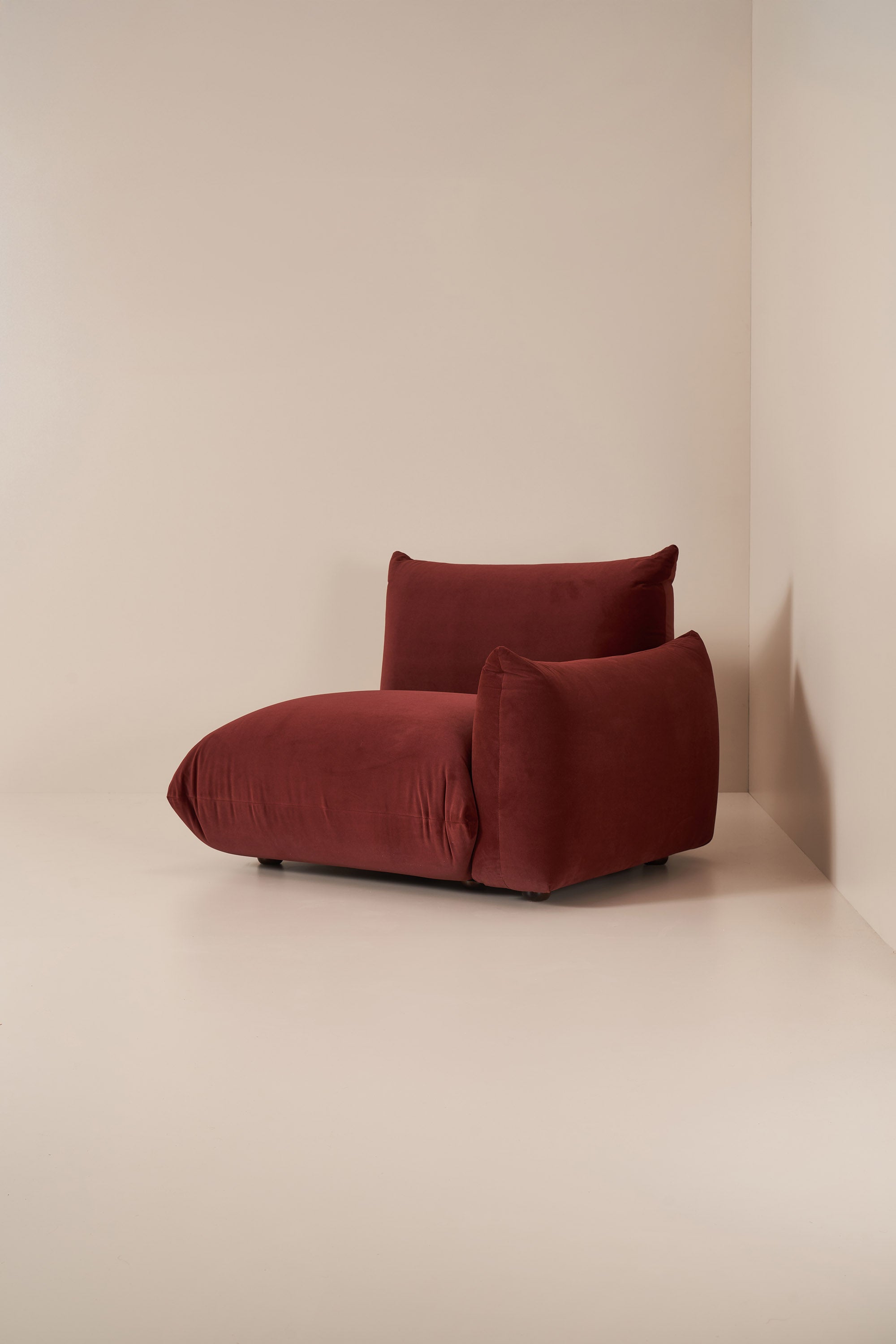 Red cushioned modular sofa against a beige wall
