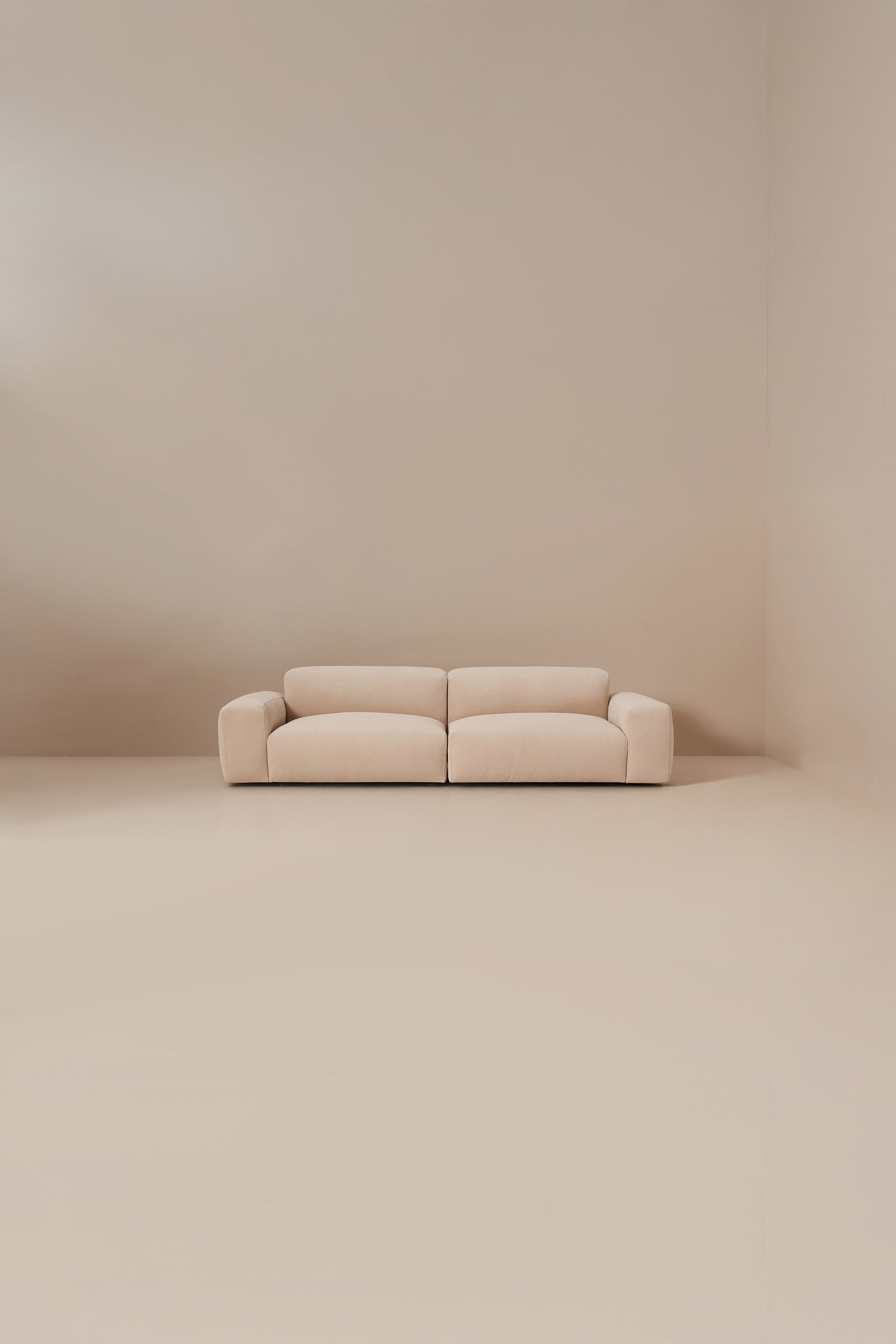 Beige modular sofa in a minimalistic room with beige walls and floor