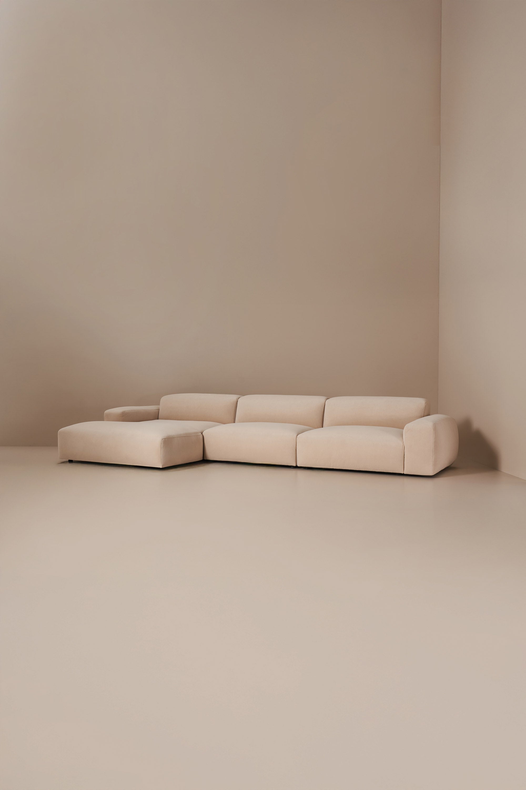 Beige sectional sofa against a plain beige wall