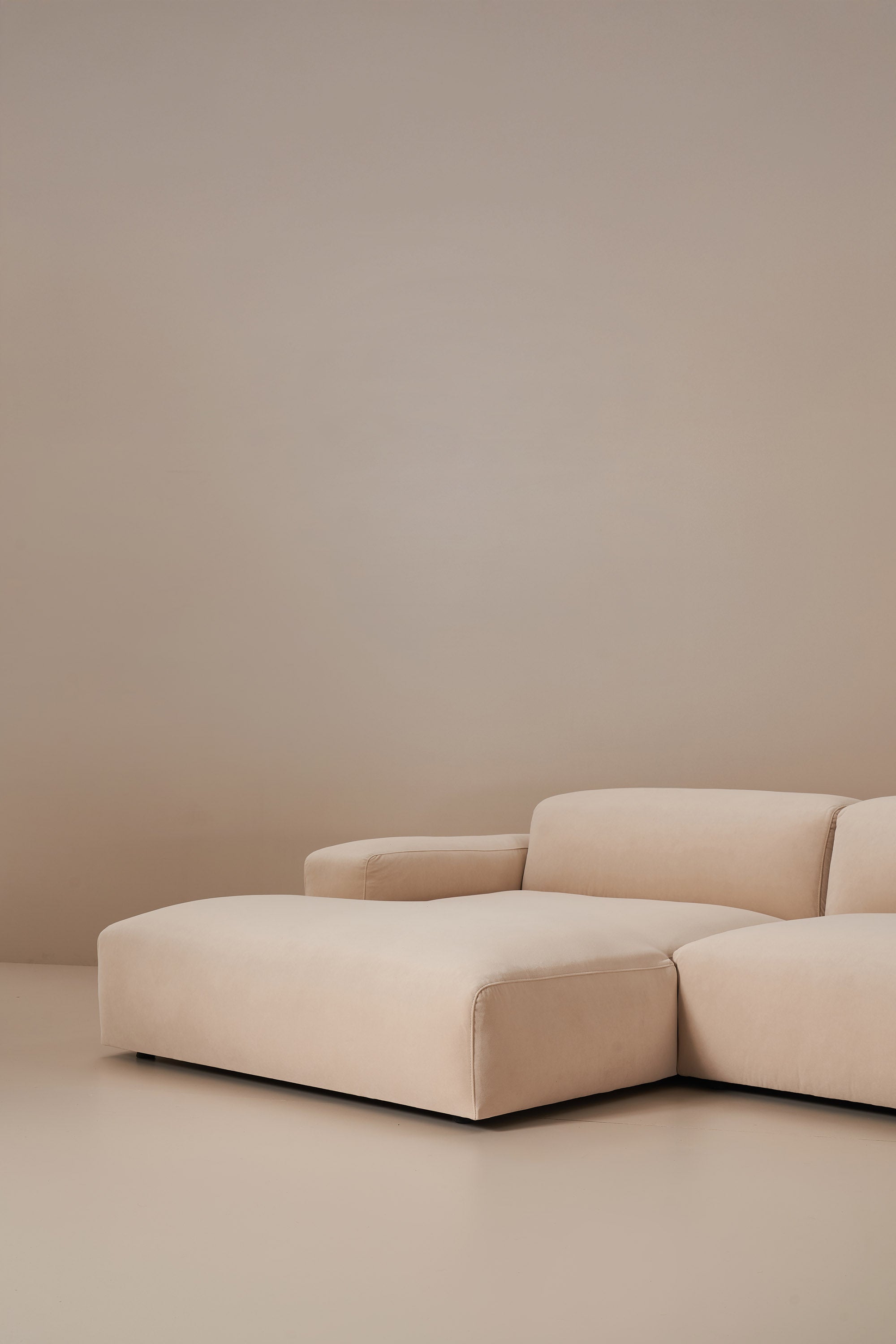 Beige sectional sofa against a plain beige wall