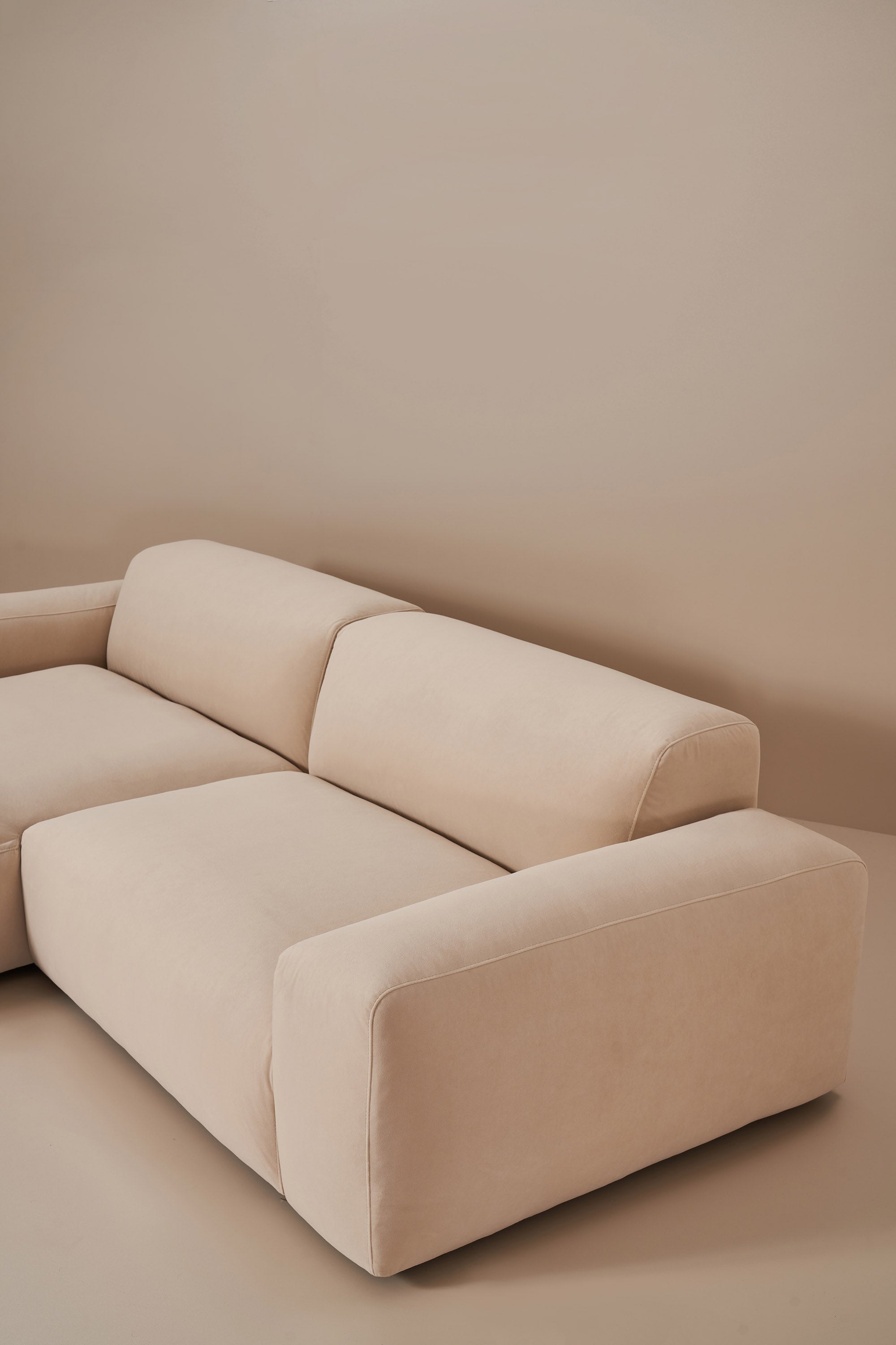 Beige sectional sofa against a plain wall
