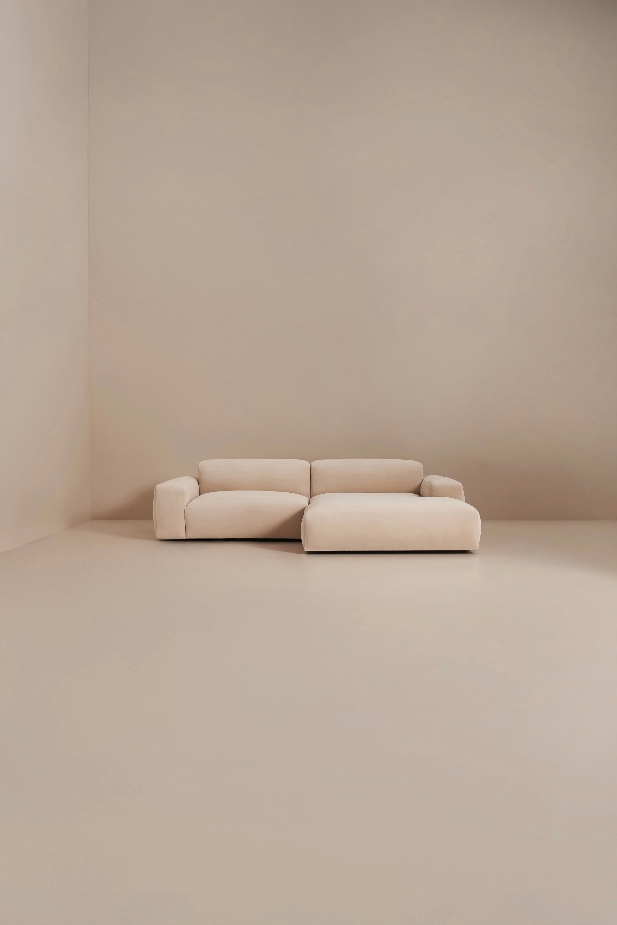 Beige sofa in a minimalistic room with beige walls and floor