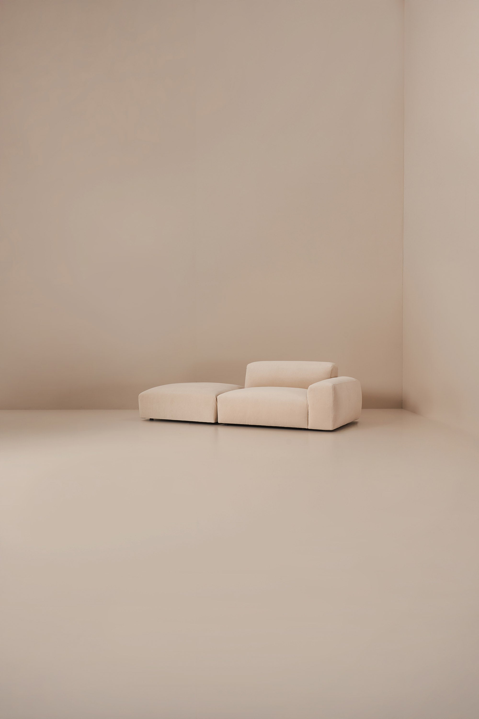 Beige sofa in a minimalistic room with beige walls and floor.