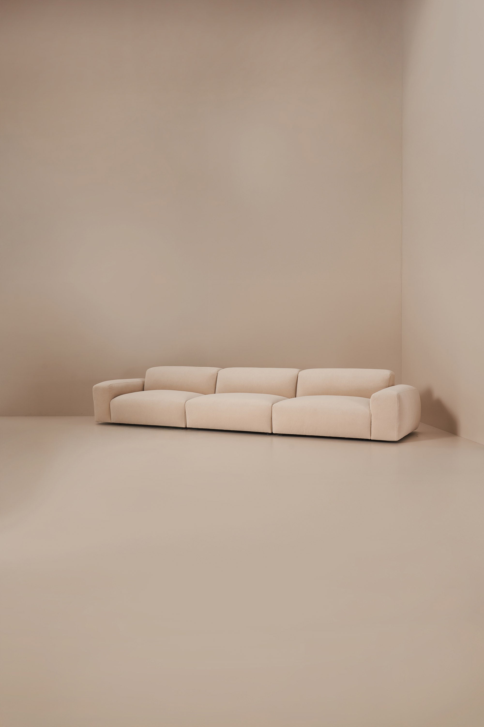 Beige sofa against a beige wall in a minimalistic setting