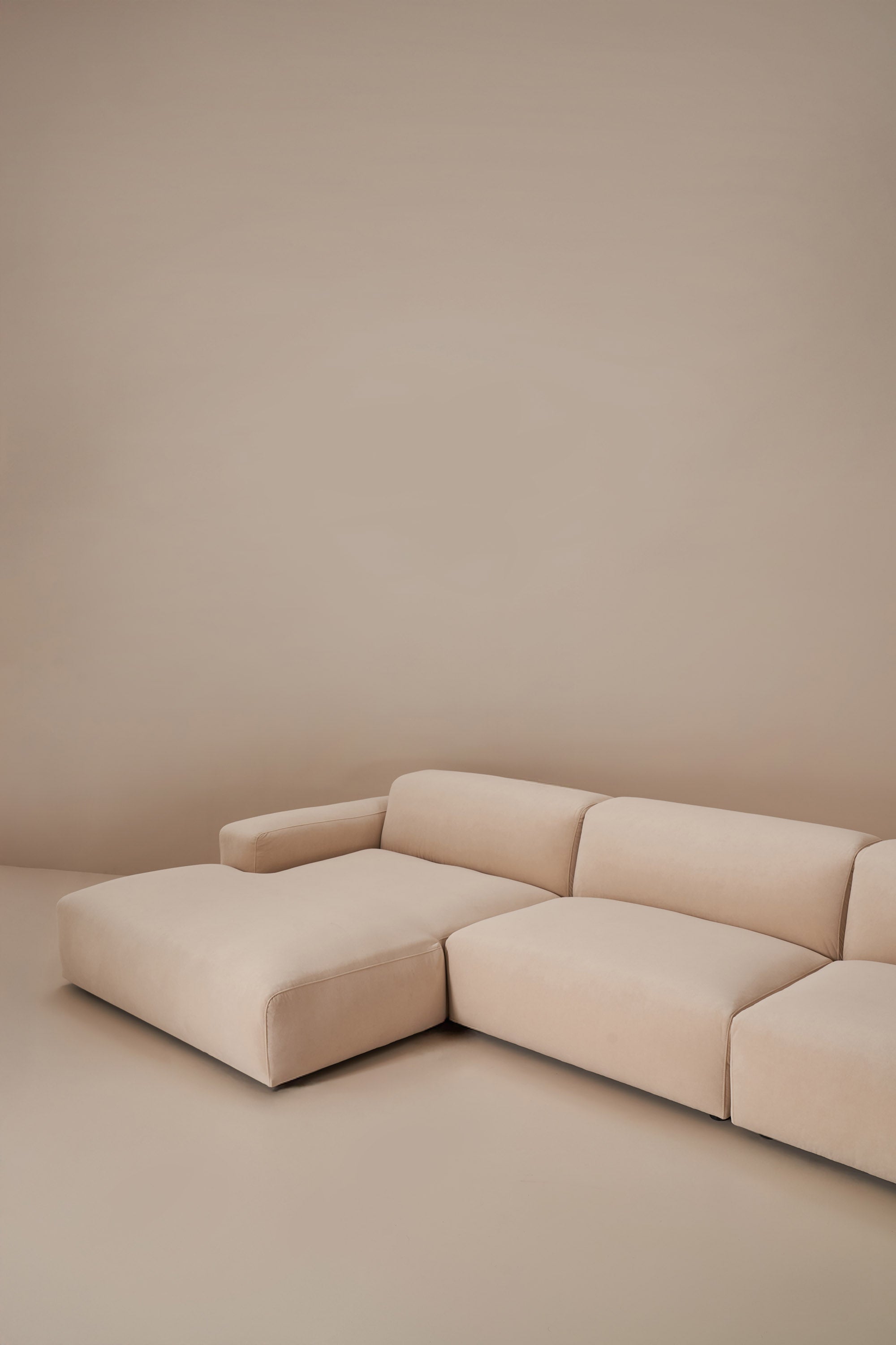 Beige sectional sofa against a plain beige wall