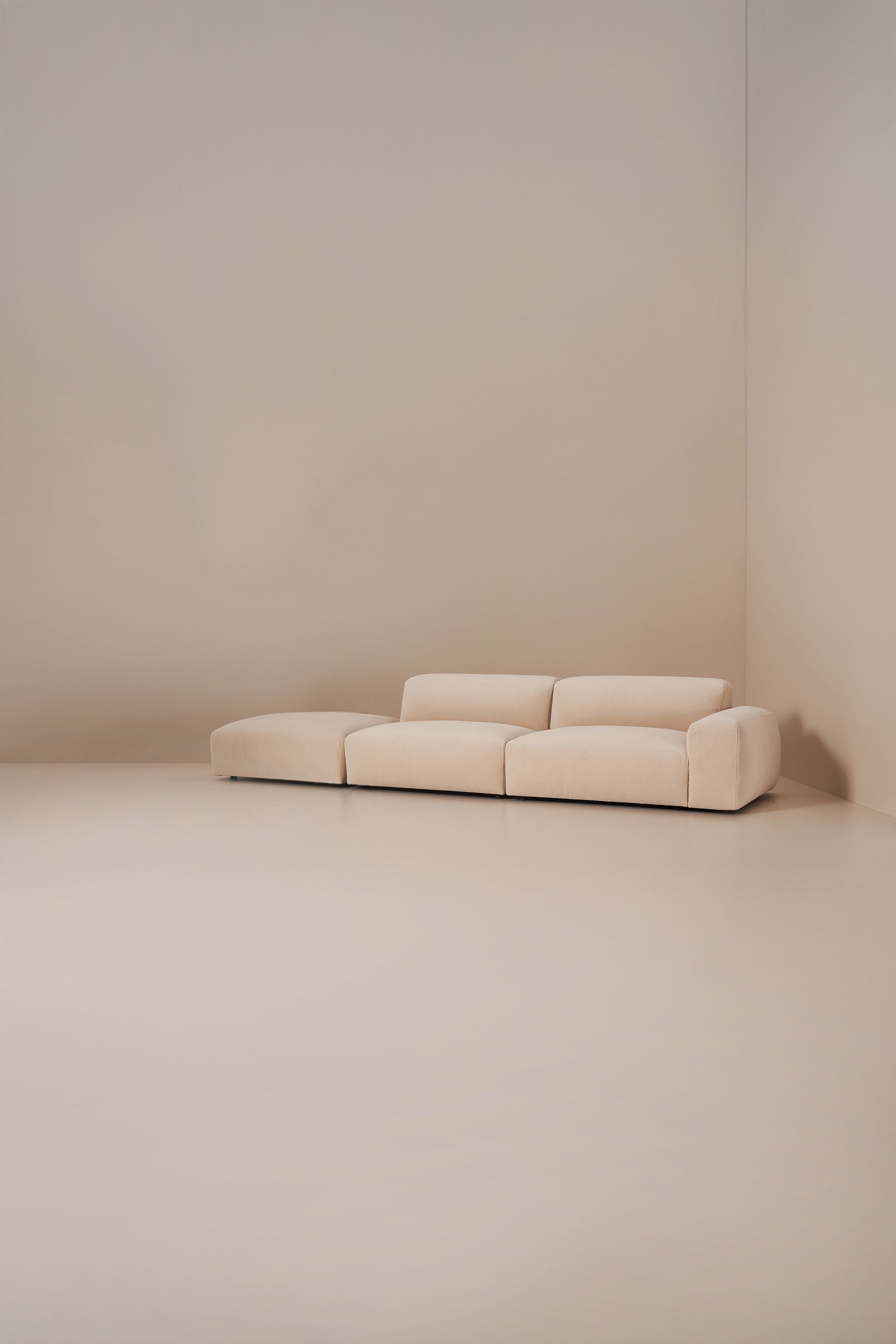 Beige sofa in a minimalistic room with beige walls and floor.