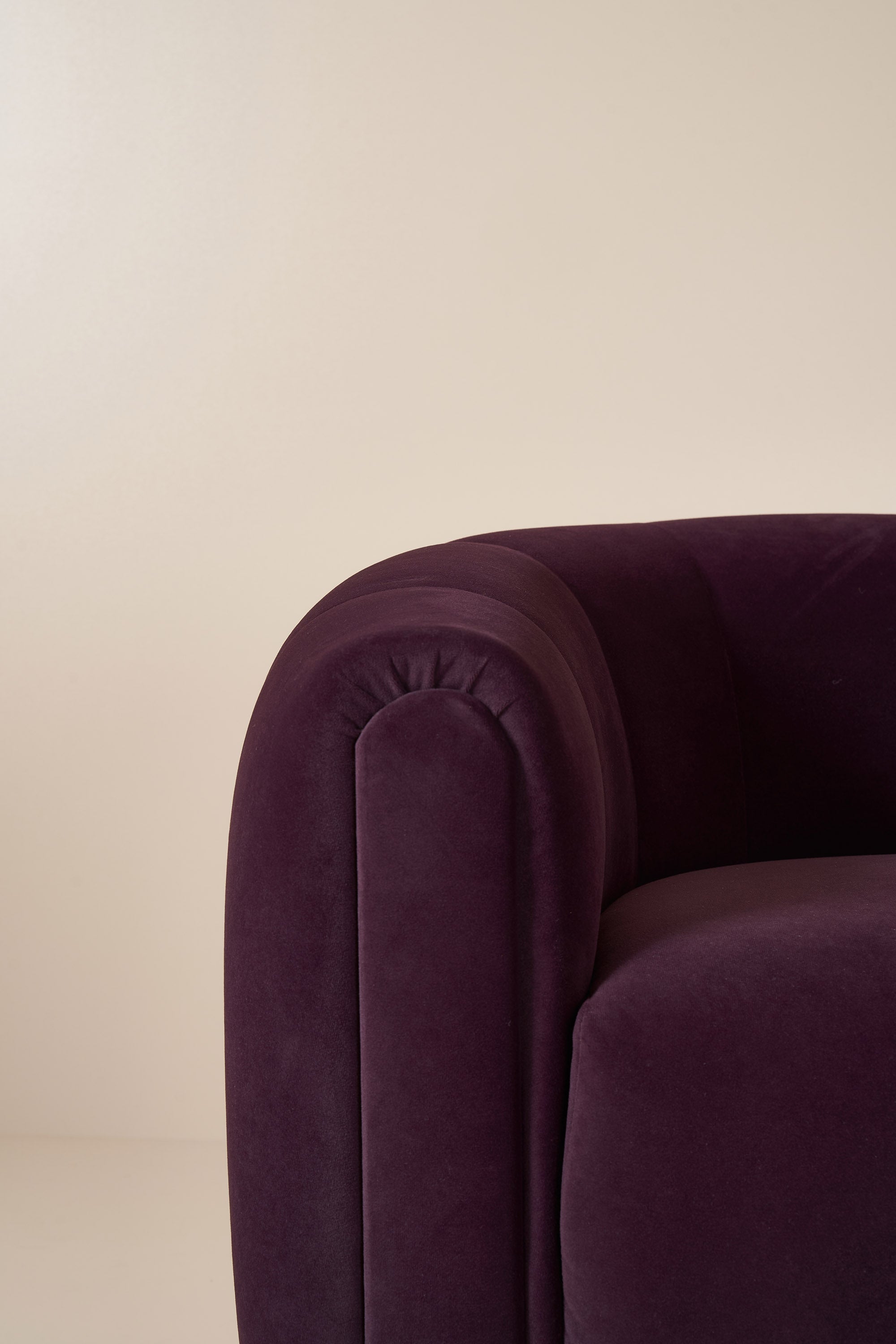 Close-up of a purple velvet armchair against a beige background